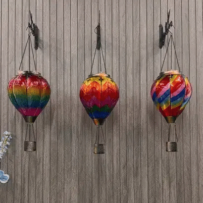 Colorful hot air balloon solar lanterns hanging in a garden during the day