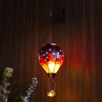 Hand-painted patriotic solar balloon lantern featuring an American flag and red cardinal bird, perfect for backyard decorations, patio décor, and garden solar lights with a warm flame-effect glow