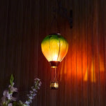 Hand-painted rainbow glass solar hot air balloon lantern for yard décor, backyard solar lights, and patio decorations with warm flame-effect illumination