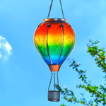 Rainbow hot air balloon lantern glowing in backyard foliage, perfect for solar garden lights and backyard solar lighting