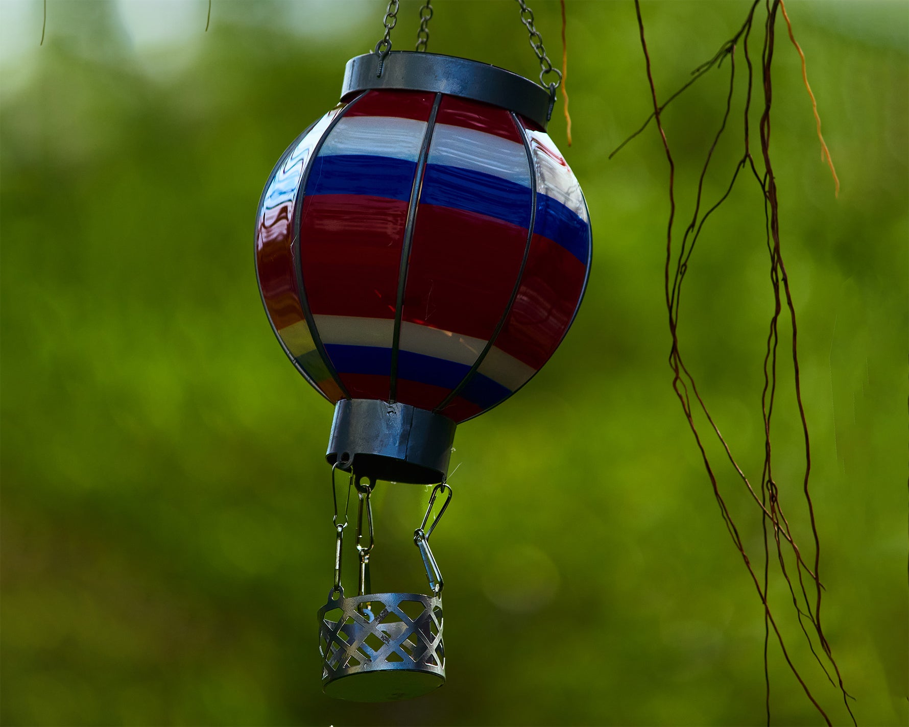 Colorful balloon solar lantern in rainbow gradient lighting up a garden path, enhancing backyard solar light experience