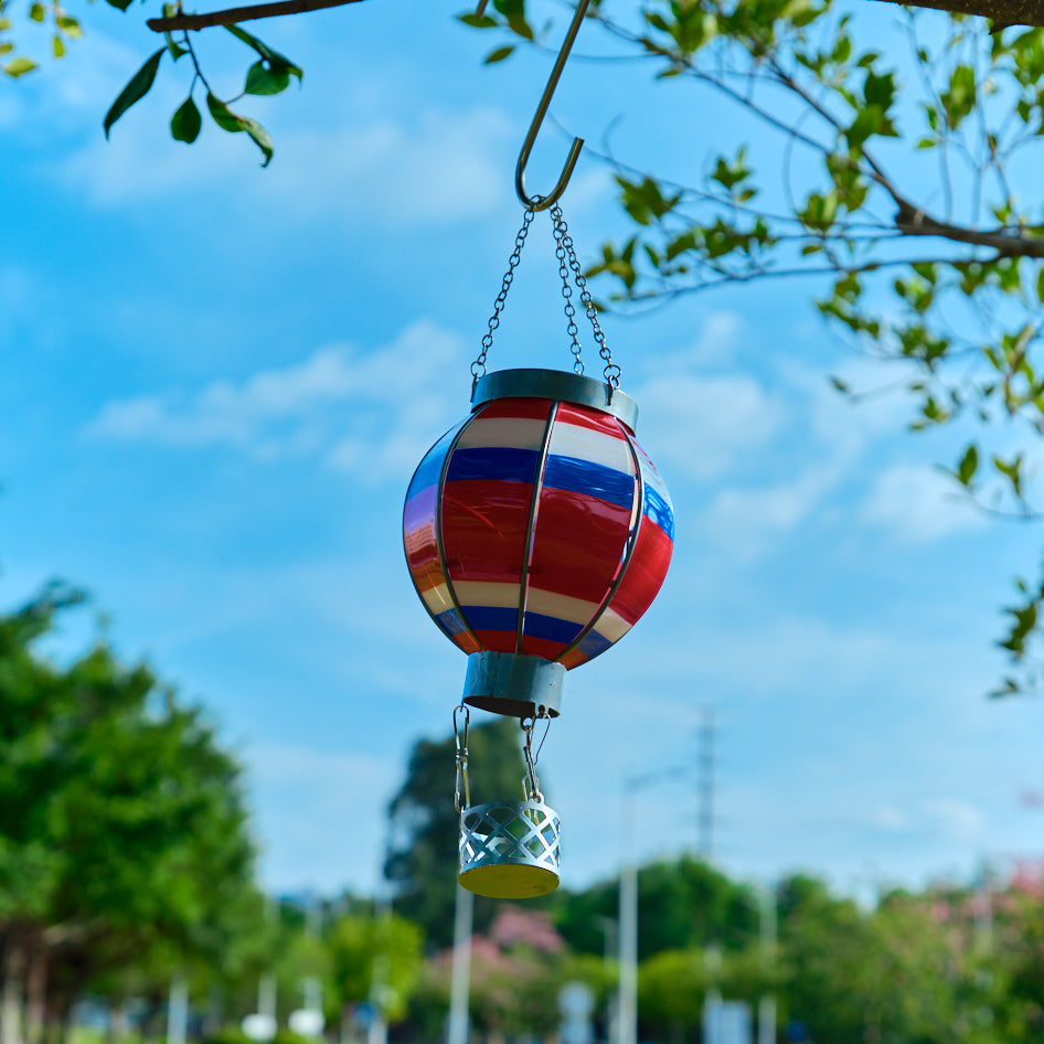 Colorful balloon solar lantern in rainbow gradient lighting up a garden path, enhancing backyard solar light experience