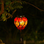 Night view of solar lantern with dragonfly motif glowing in a landscaped garden, great for front yard decor