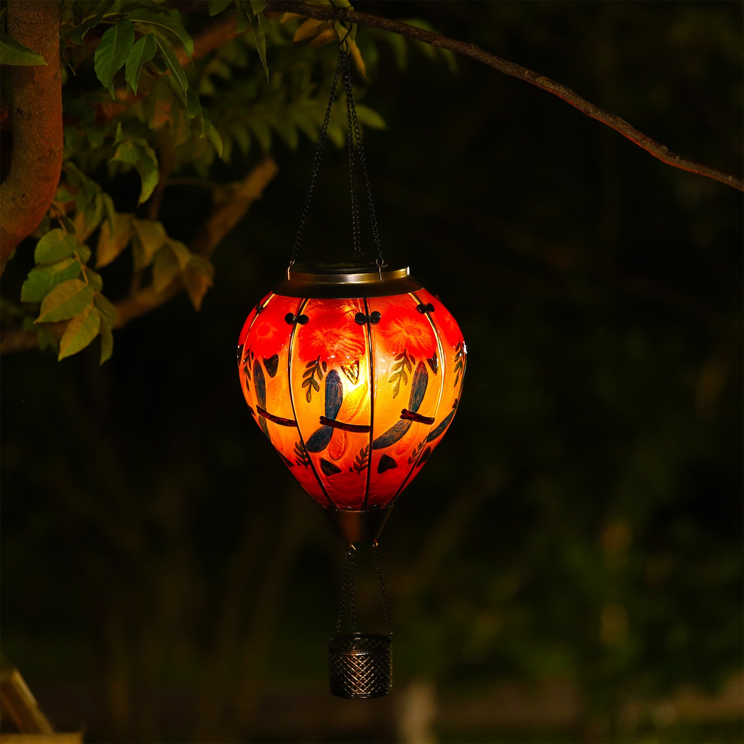 Night view of solar lantern with dragonfly motif glowing in a landscaped garden, great for front yard decor