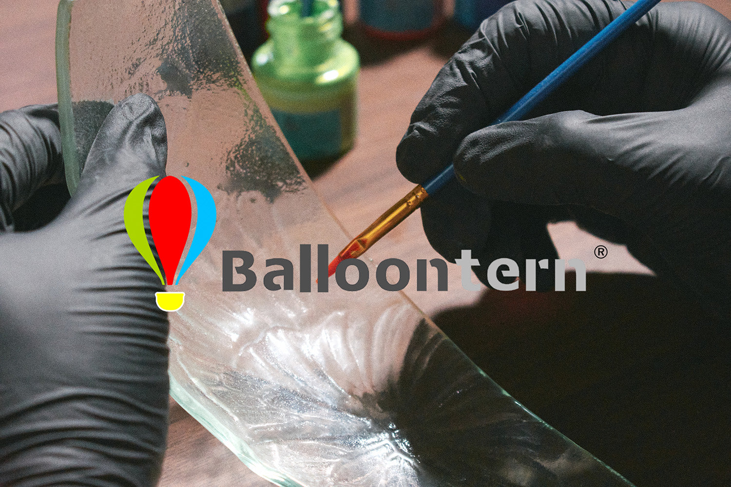 Skilled artisan painting gradient colors on curved glass panels for handcrafted solar balloon lanterns