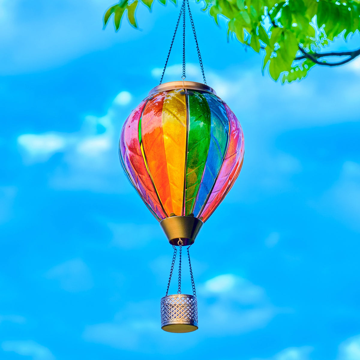 Classic rainbow hot air balloon solar lantern displayed in a colorful yard during the day